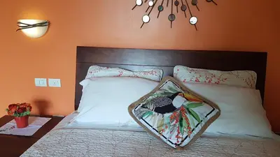 a bedroom with a bed with white sheets and pillows at Tacacori EcoLodge in Alajuela City