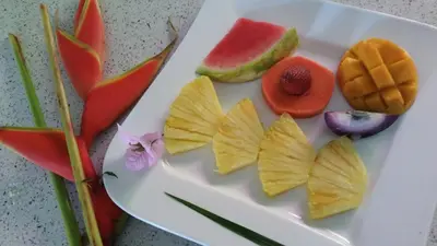 a white plate with fruits and vegetables on a table at Tacacori EcoLodge in Alajuela City