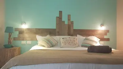 a bedroom with a large bed with white sheets and pillows at Tacacori EcoLodge in Alajuela City