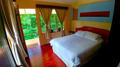 a bedroom with a white bed and a window at Agua Inn in Nuevo Arenal