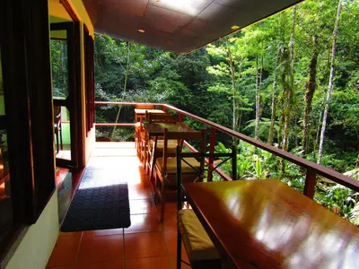 a balcony with a table and chairs and trees at Agua Inn in Nuevo Arenal
