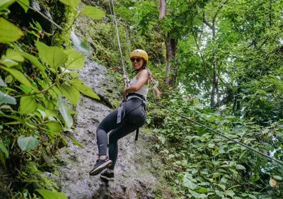 a woman on a zip line in the jungle at Montaña de fuego Mountain Resort & Spa in Fortuna