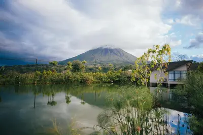 a mountain in the distance with a house and a lake at Montaña de fuego Mountain Resort & Spa in Fortuna