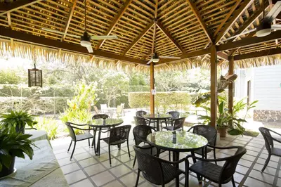 a patio with tables and chairs under a wooden pergola at Hotel Villa Los Candiles in San José