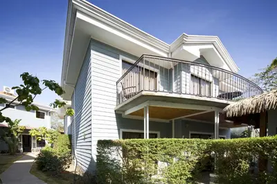 a white house with a balcony and bushes at Hotel Villa Los Candiles in San José