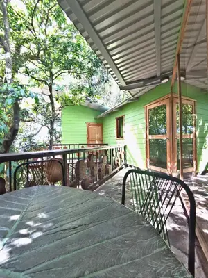 a green house with a table on a deck at Canopy Wonders Vacation Home in Monteverde Costa Rica