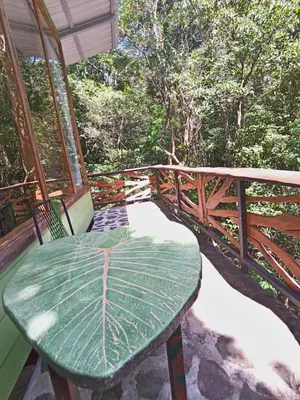 a green table on a balcony with an umbrella at Canopy Wonders Vacation Home in Monteverde Costa Rica