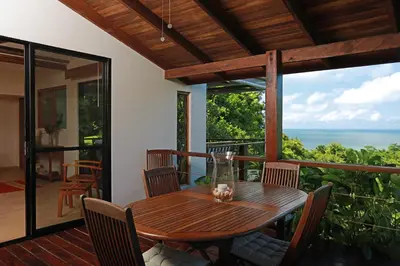 a wooden table on a balcony with a view of the ocean at Casa Frangipani in Montezuma