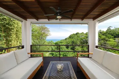 a screened in porch with a view of the ocean at Casa Frangipani in Montezuma