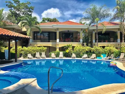 a swimming pool in front of a house at Monte Carlo Luxury Condominiums in Jacó