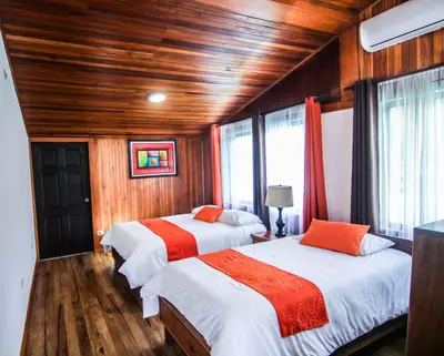 two beds in a room with wooden walls and wood floors at Mar Inn Costa Rica in Monteverde Costa Rica