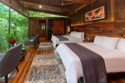two beds in a room with wooden walls at Ecolirios Boutique Hotel & Villas in Guácimo