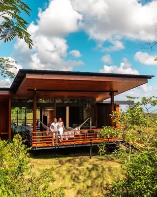two people sitting on the porch of a house at Ecolirios Boutique Hotel & Villas in Guácimo