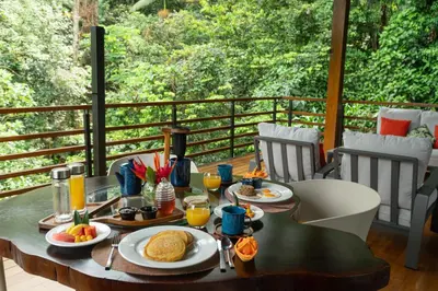 a table with breakfast food on top of a balcony at Ecolirios Boutique Hotel & Villas in Guácimo