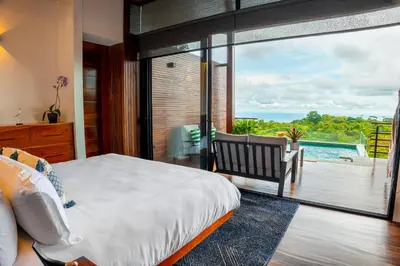 a bedroom with a bed and a view of a pool at Ecolirios Boutique Hotel & Villas in Guácimo