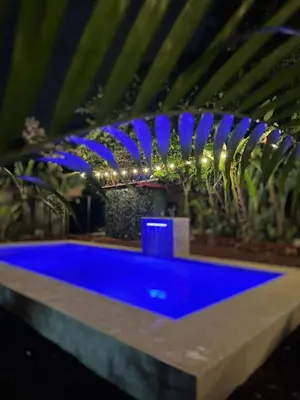 a blue pool in a garden with blue lights at ApartHotel Villa Pacande & Rooms in Alajuela City