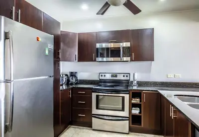 a kitchen with wooden cabinets and a stainless steel refrigerator at Oceanfront The Palms Jaco in Jacó