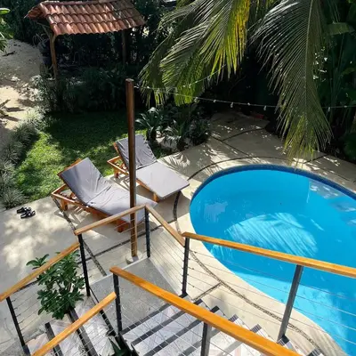 a swimming pool with a chair and a chaise lounge next to it at El Chante Surf House in Santa Teresa Beach