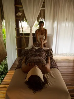 a man sitting on a bed with a woman laying on it at El Chante Surf House in Santa Teresa Beach