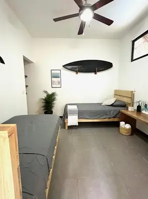 a bedroom with two beds and a ceiling fan at El Chante Surf House in Santa Teresa Beach