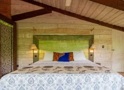 a bedroom with a large bed with a wooden wall at Latica Lodge in Playa Negra