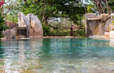a pool of water with a waterfall and rocks at Latica Lodge in Playa Negra