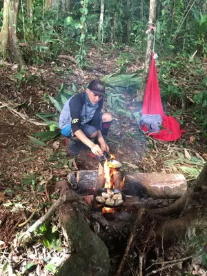 a man cooking over a fire in the woods at Iguanitas Lodge in Pital