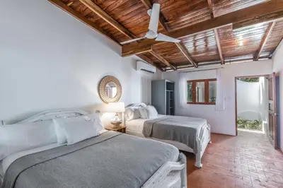 a bedroom with two beds and a ceiling fan at Nosara Beach Hotel in Nosara