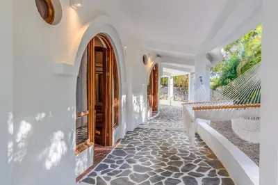 a white house with a porch with a hammock at Nosara Beach Hotel in Nosara