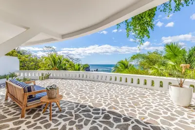 an outdoor patio with a bench and a view of the ocean at Nosara Beach Hotel in Nosara