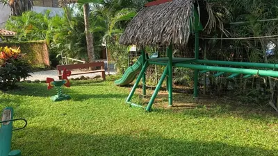 a playground with a green slide in the grass at Esencia Hotel and Villas in Santa Teresa Beach