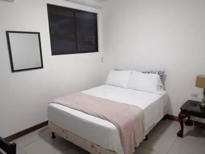 a white bedroom with a bed and a picture on the wall at Apartotel Don Francisco in San José
