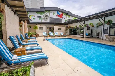 a pool with chaise lounge chairs next to a building at KC Hotel San Jose in San José