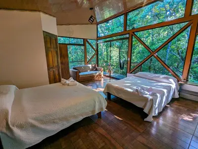 a bedroom with two beds in a room with large windows at Quality Cabins Monteverde in Monteverde Costa Rica