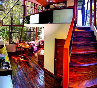 a living room with a staircase in a house at Quality Cabins Monteverde in Monteverde Costa Rica