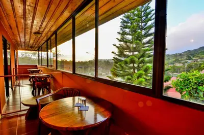 a restaurant with a table and chairs and a large window at Hotel Cipreses in Monteverde Costa Rica