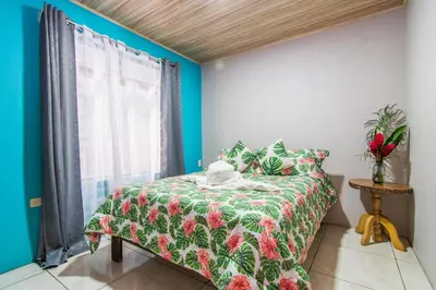 a bedroom with a bed with a green comforter and a window at Casa Monarca II - Monteverde in Monteverde Costa Rica
