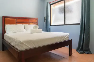 a bed with a wooden headboard and a window at Bongo - Adults Only in Manuel Antonio