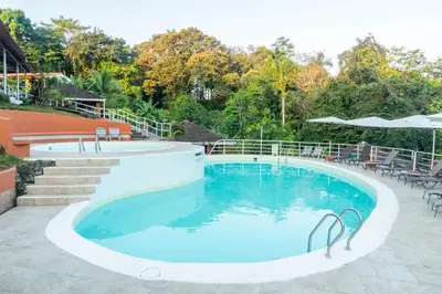 a large swimming pool with stairs and tables and chairs at Bongo - Adults Only in Manuel Antonio