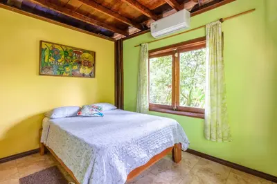 a bedroom with green walls and a bed with a window at casa chilamates in Tortuguero