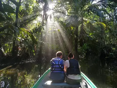 two people sitting on a boat in the jungle at casa chilamates in Tortuguero