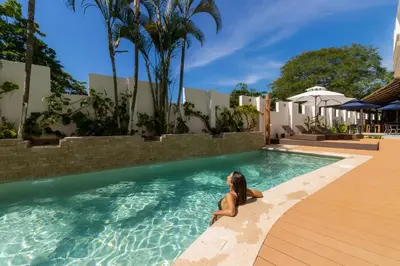 a woman sitting in a swimming pool at Hotel Santa Teresa by the Beach in Santa Teresa Beach