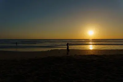 a person standing on the beach at sunset at Hotel Santa Teresa by the Beach in Santa Teresa Beach