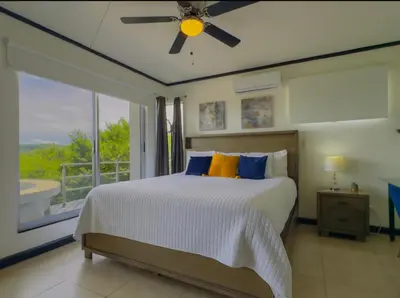 a bedroom with a bed with a ceiling fan and a window at Gorgeous Ocean View Private home, 4 bedrooms with en suite, private plunge pool in Coco