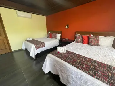a hotel room with two beds and orange walls at Campos Arenal Hotel in Fortuna