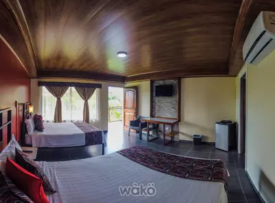 a hotel room with two beds and a desk at Campos Arenal Hotel in Fortuna