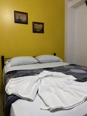 two beds in a room with yellow walls at Hotel Quinta Avenida in San José