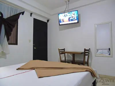 a bedroom with a bed and a tv on the wall at Hotel Quinta Avenida in San José