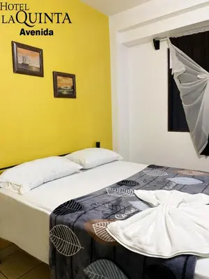 two beds in a room with a yellow wall at Hotel Quinta Avenida in San José