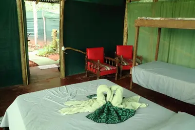 a bedroom with two beds and two red chairs at Isla Violin Eco-Lodge in Isla Violin